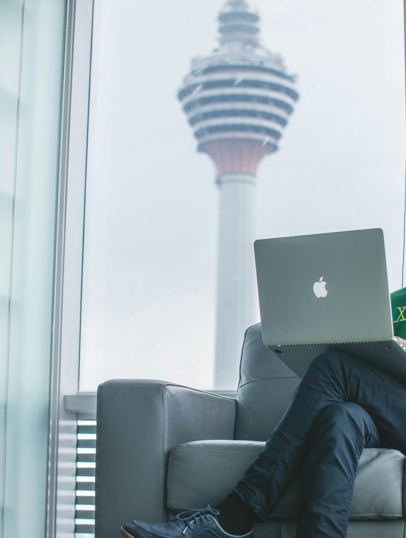Remote worker on a laptop with the KL Tower in the window